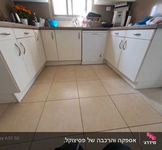 מטבח עם ארונות לבנים ומשטח עבודה